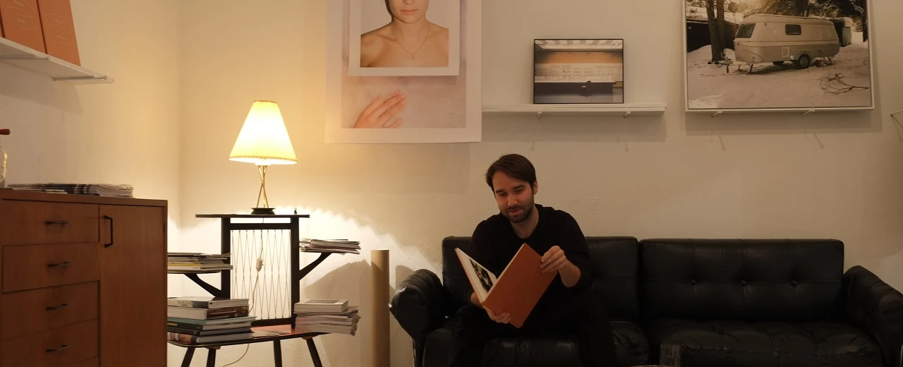 Mann liest Buch auf Sofa in Galerie mit Bildern.