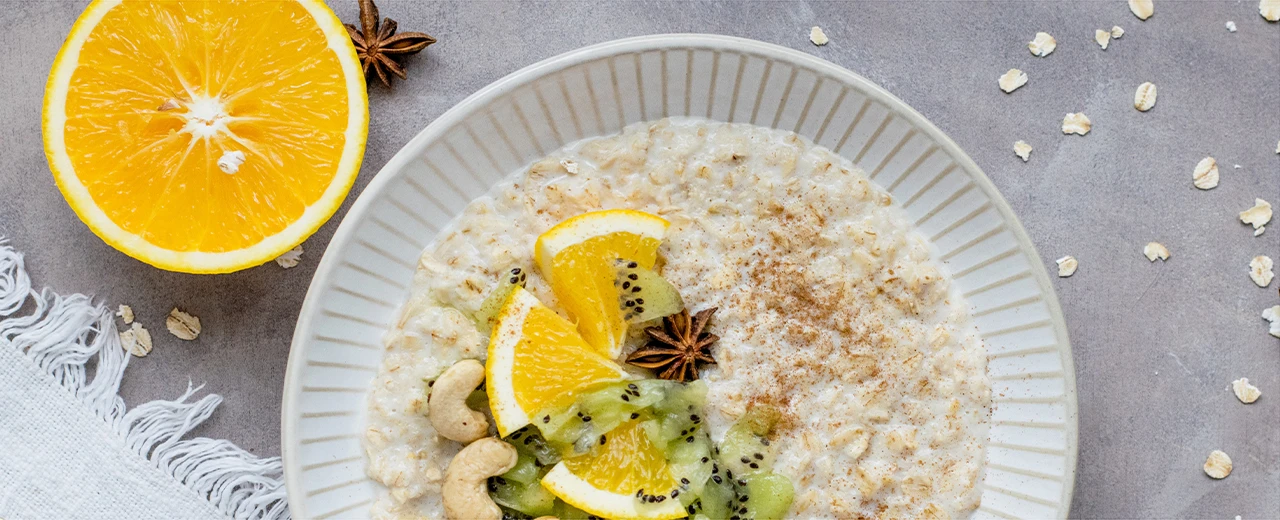Foto von Haferflocken mit Orangen, Kiwi und Cashewnüssen. Gesundes Frühstück.