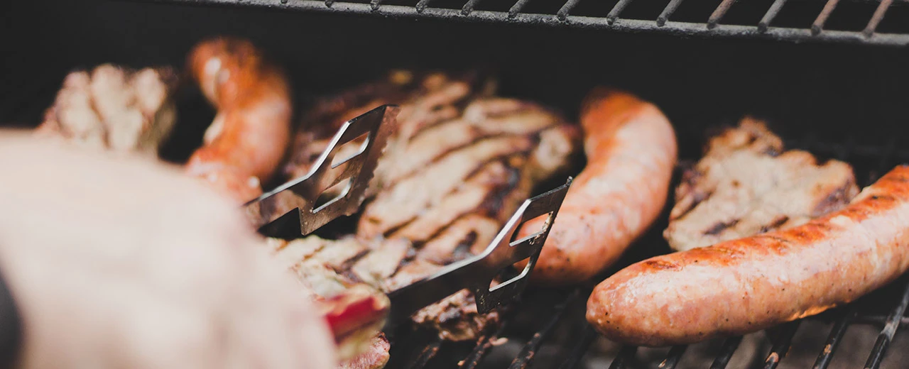 © ANDRIK LANGFIELD PETRIDES on Unsplash Nahaufnahme von Bratwürsten und Fleisch auf einem heißen Grill, bearbeitet mit Adobe Photoshop.