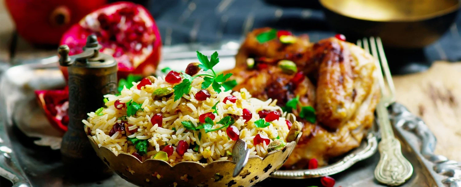 © Unsplash Appetitliches Foto von Reis mit Granatapfel und Pistazien, dazu gebratenes Hähnchen.  Erstellt mit Adobe Photoshop CS6.