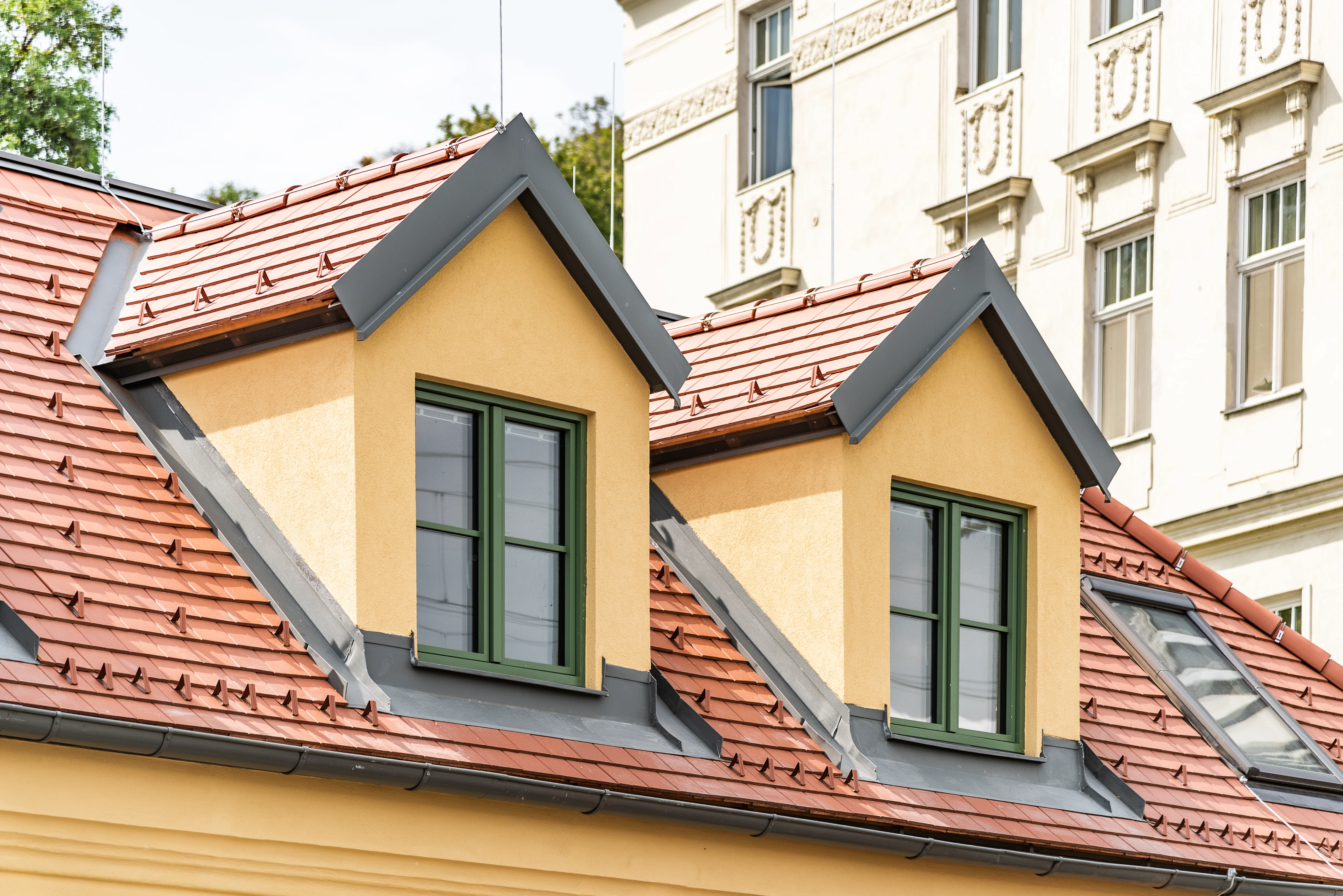 Dachfenster von gelbem Haus mit grünen Fenstern