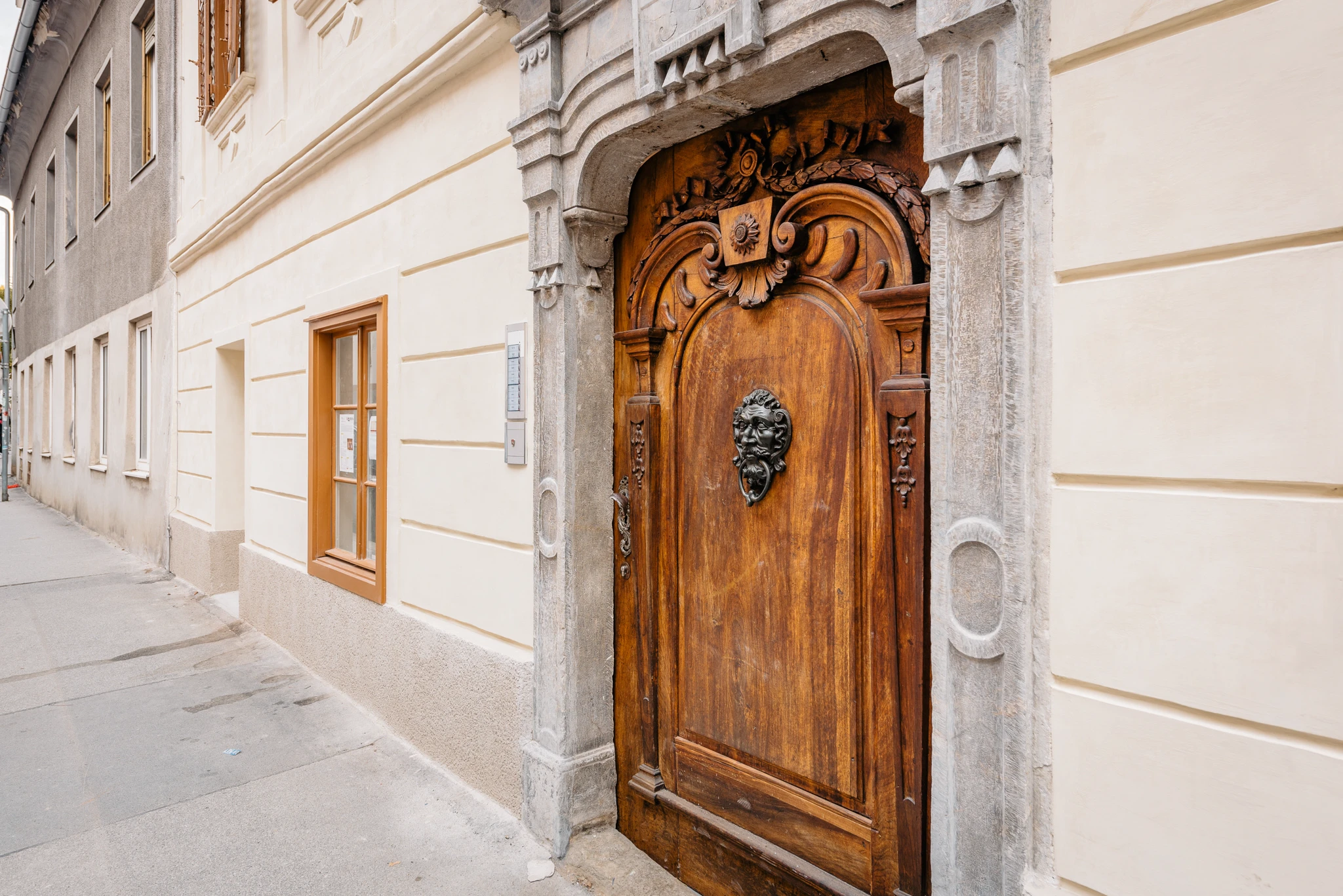 Altbau Fassade Graz mit kunstvoller Holztüre und Türklopfer aus Metall