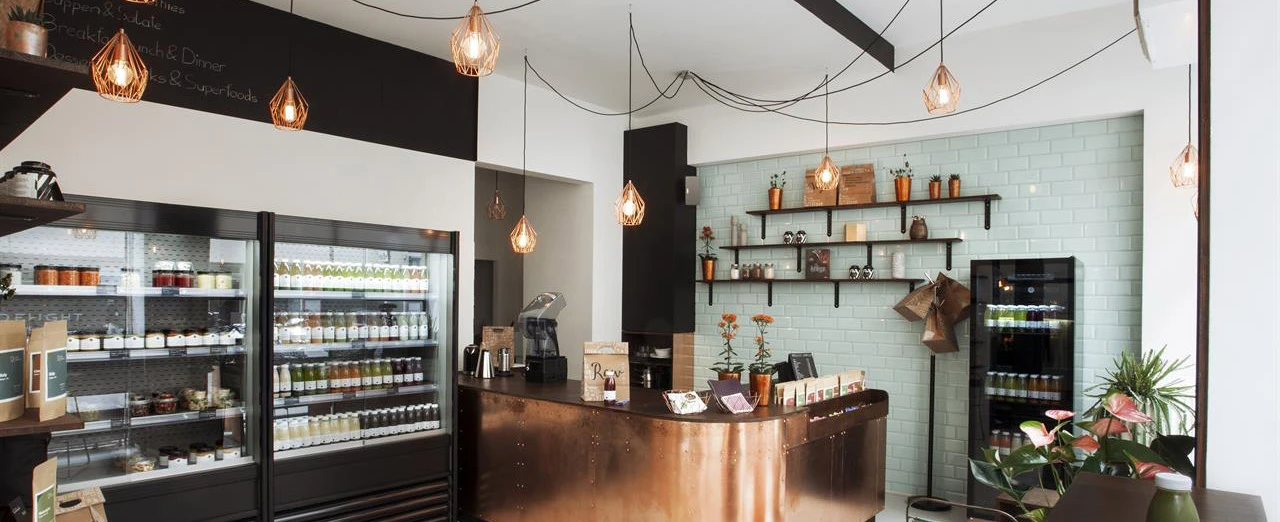 Modernes Juice-Bar-Design mit Kupfertheke, Kühlschränken & stilvoller Beleuchtung. Gesunde Säfte & Snacks.