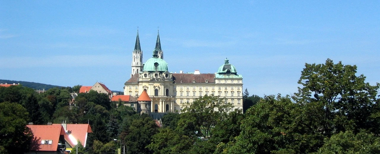 Stift Göttweig, Österreich: Barocke Abtei mit zwei Türmen und grünen Kuppeln, umgeben von Bäumen.