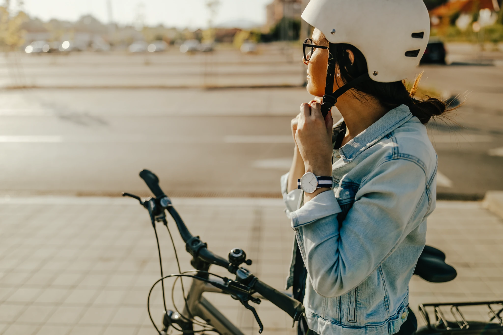Frau steht neben Fahrrad auf einer Straße und schließt ihren Helm