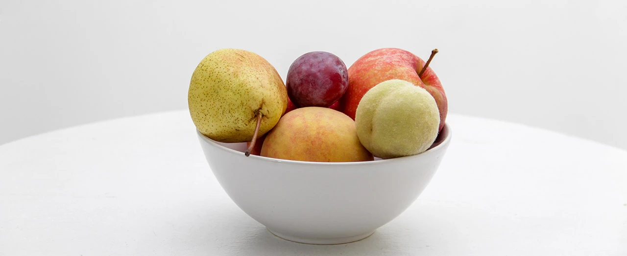 Weiße Schüssel mit Birne, Pflaume, Apfel und Pfirsich auf weißem Hintergrund. Mit Adobe Photoshop bearbeitet.