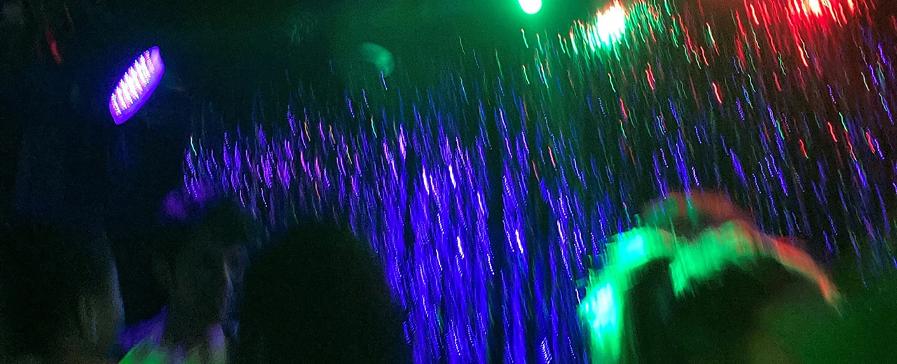 © Tabea Widmann Verschwommene Disco-Szene mit bunten Lichtern und tanzenden Personen.  Erstellt mit Adobe Photoshop.