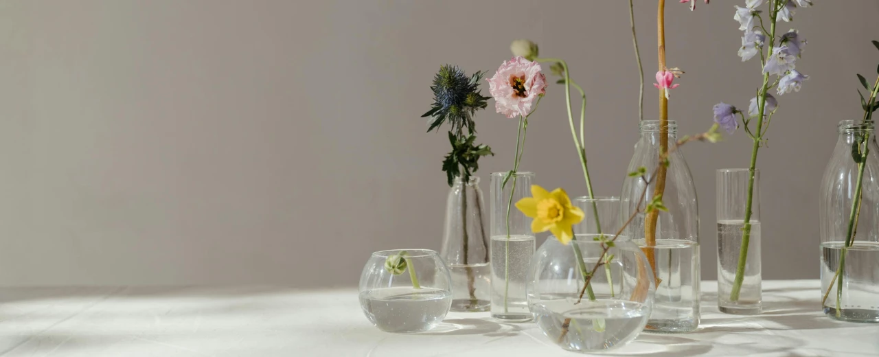 Blumenarrangement in Glasvasen. Minimalistische Dekoration mit verschiedenen Blumenarten.