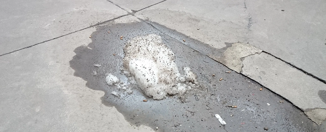 © Miriam Kummer Schmutziger Bürgersteig mit Restschnee, Pfütze & Zigarettenkippen.