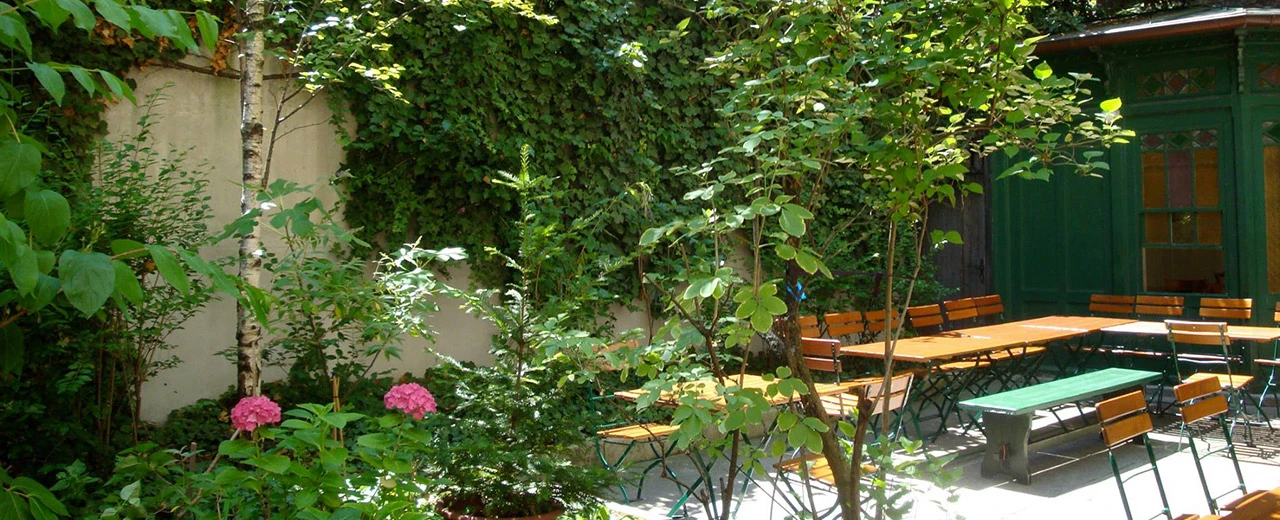 Idyllischer Biergarten mit Tischen, Stühlen und viel Grün. Perfekt zum Entspannen.