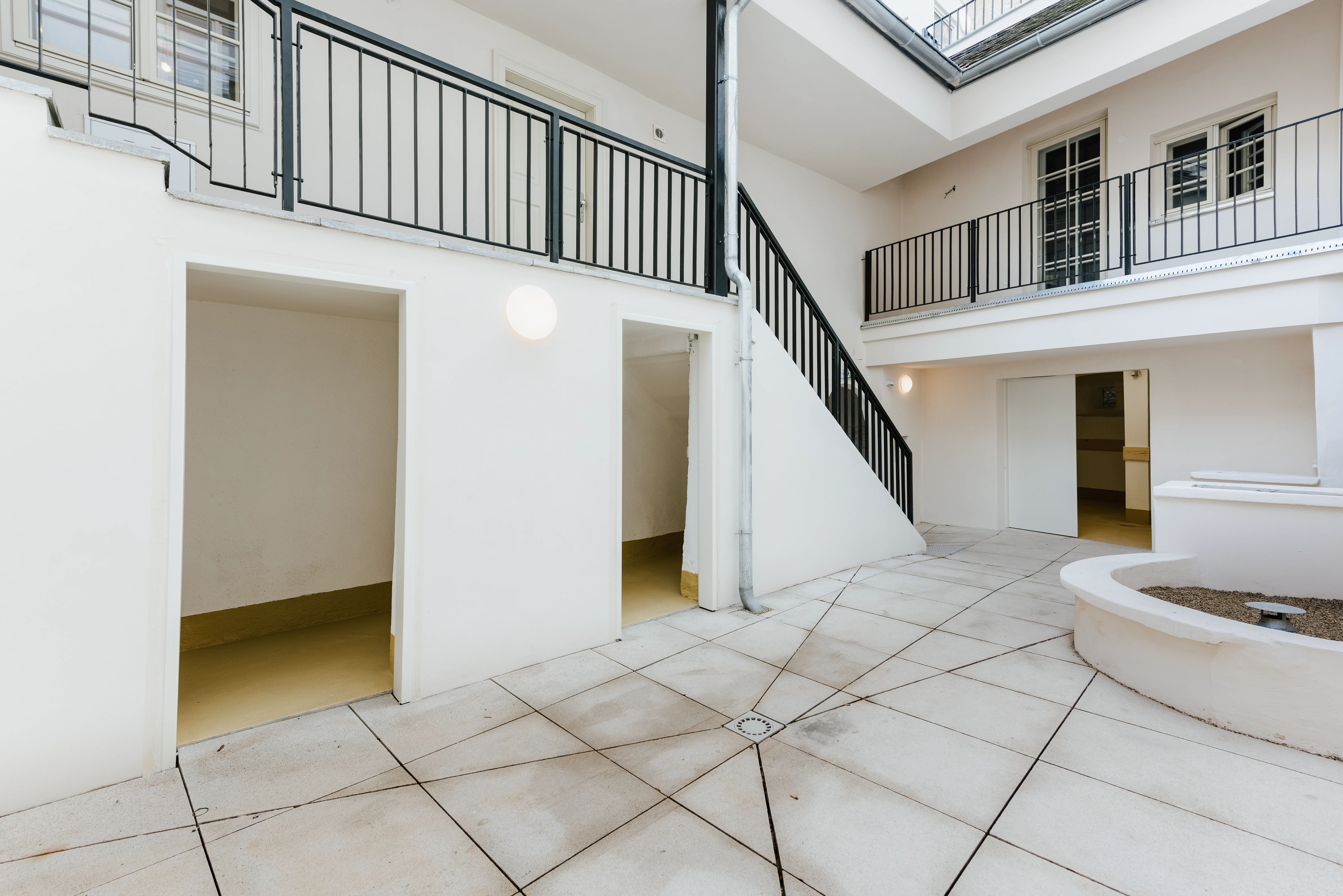 Heller Innenhof mit schwarzem Metallgeländer