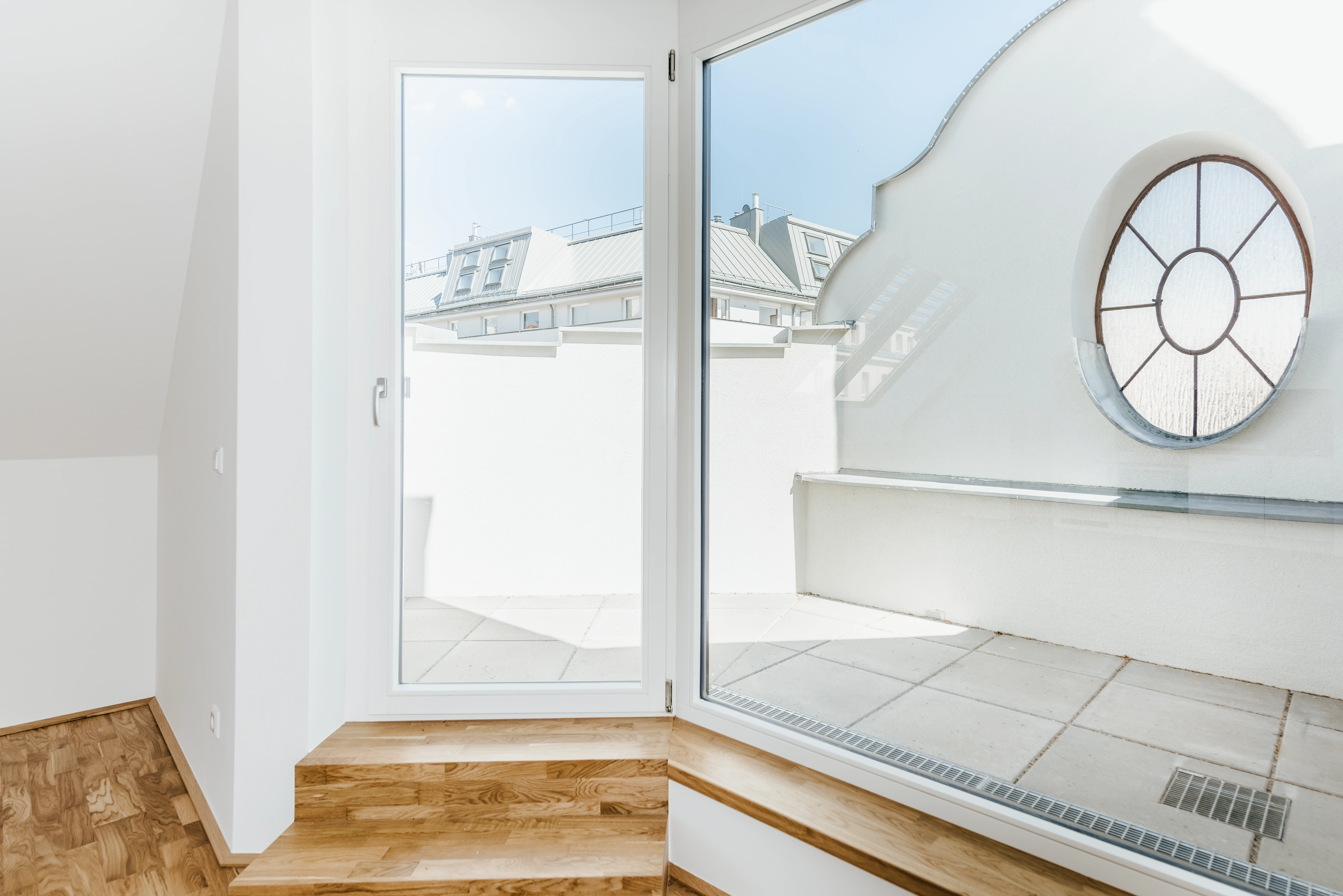 Sicht aus Wohnzimmer auf Dachterrasse mit rundem Fenster