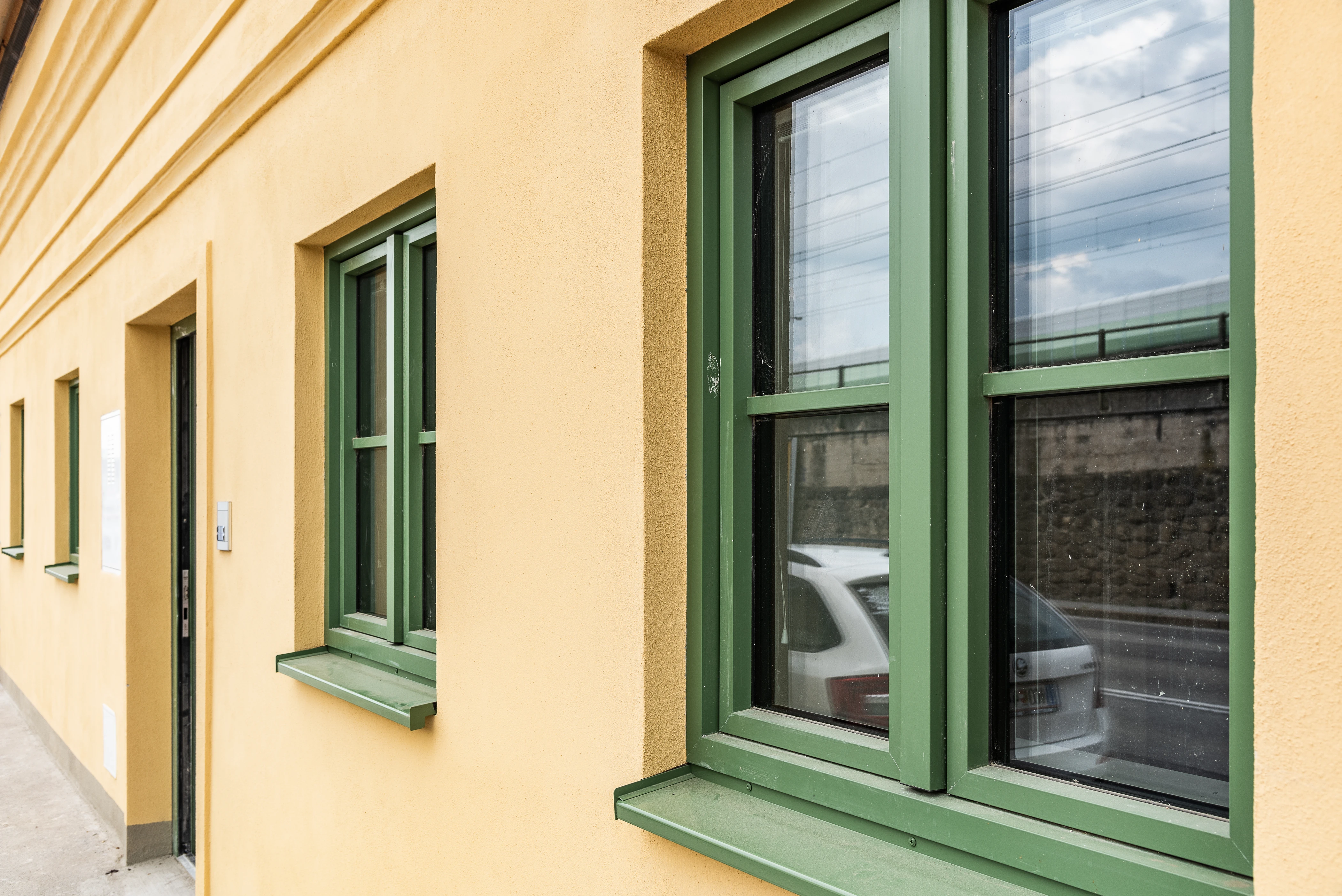 Fensterfront von gelbem Haus mit grünen Fenstern