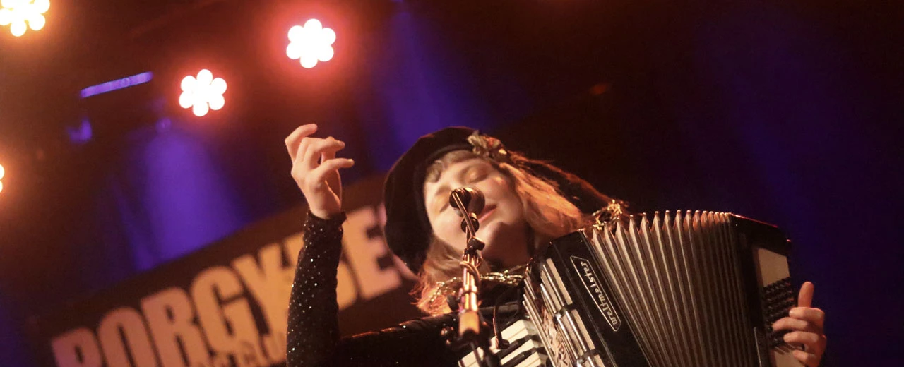 Musikerin spielt Akkordeon auf der Bühne, Konzertfotografie mit Bühnenbeleuchtung.