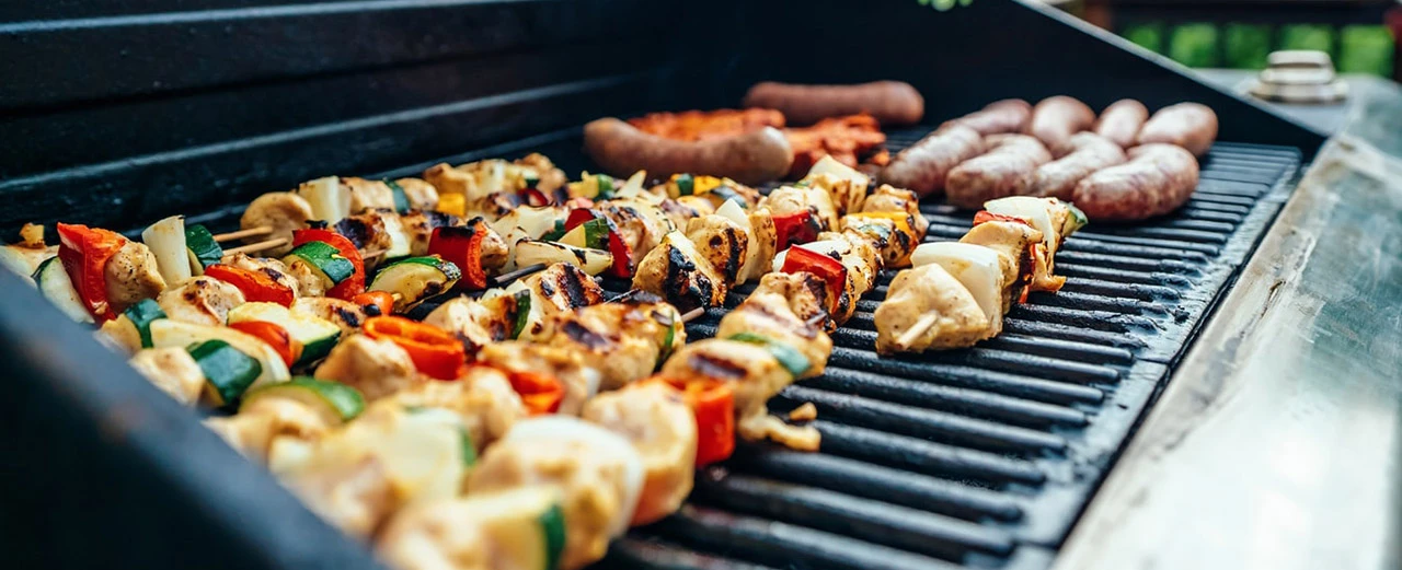 Hähnchenspieße und Würste auf dem Grill. Leckeres BBQ-Essen im Sommer.