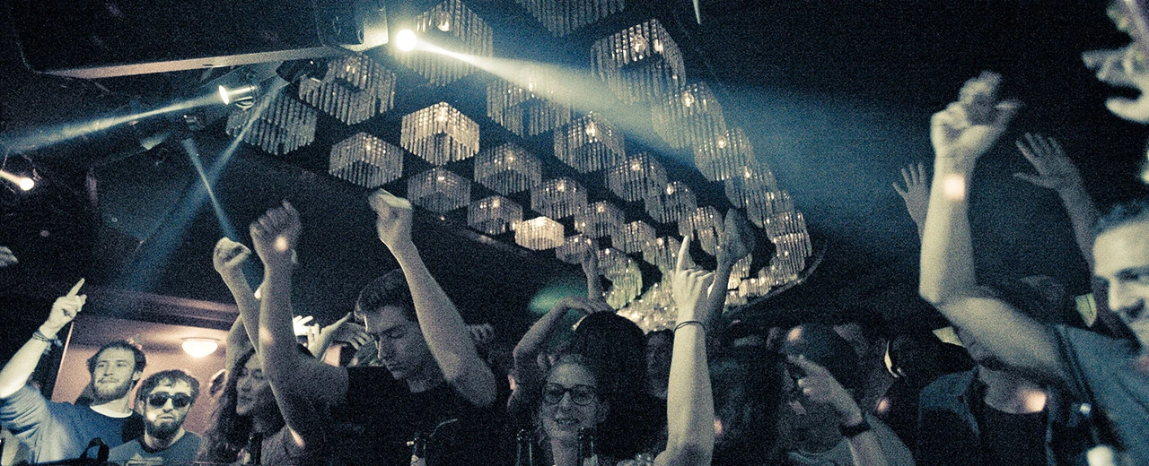 © Claudio Farkasch Foto von tanzenden Menschen in einem Nachtclub unter einer großen Kristall-Kronleuchter. © Claudio Farkasch/lichtschalter.tv