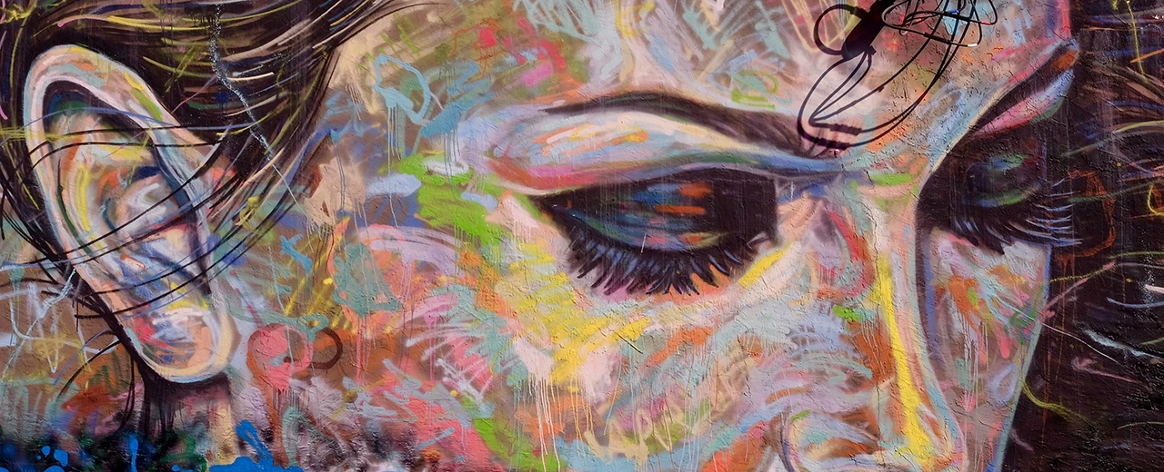 Ausdrucksstarkes Graffiti-Porträt eines Teils eines weiblichen Gesichts mit leuchtenden Farben und dynamischen Pinselstrichen.