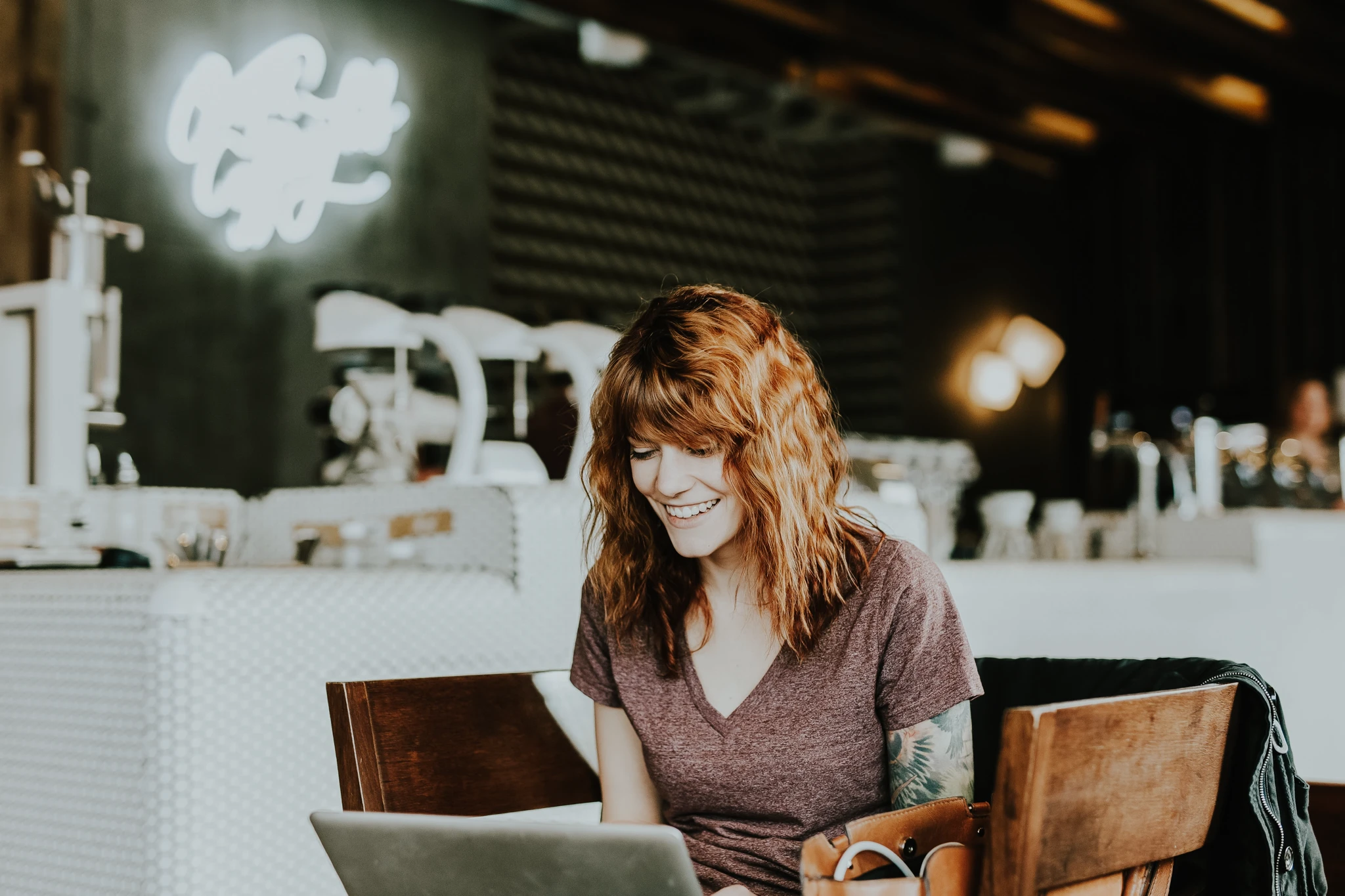 Frau sitzt in Cafe am Laptop und freut sich über Steueroptimierung mit Immobilieninvestments