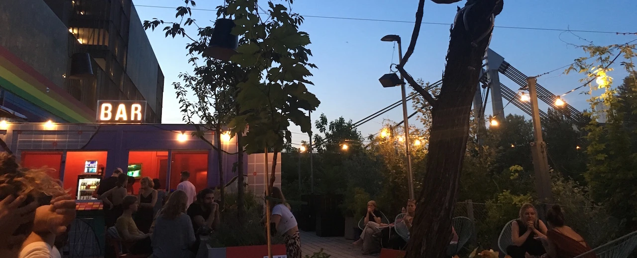 Gemütliche Abendatmosphäre in einer Outdoor-Bar mit Menschen und Pflanzen. Entspannte Stimmung.