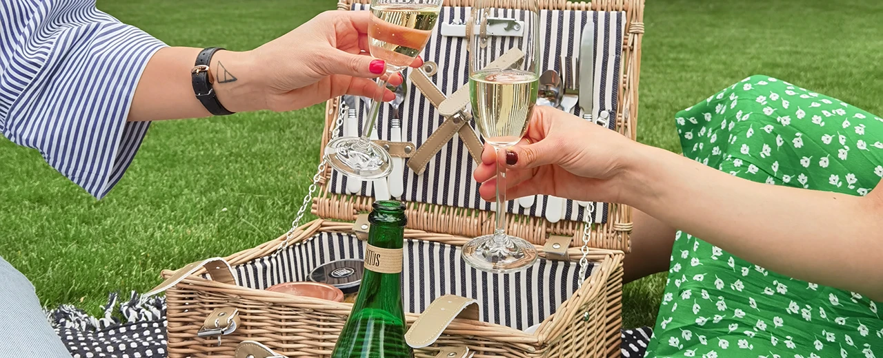 Zwei Personen genießen ein Picknick im Grünen mit Sekt. Sommerliche Stimmung.