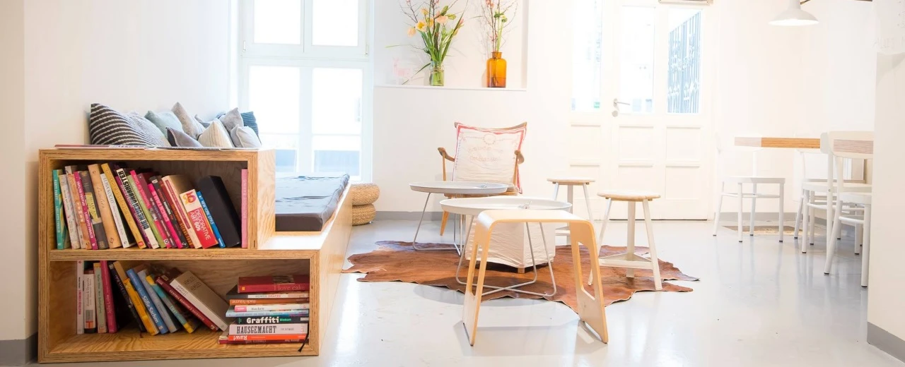 Helles, minimalistisches Wohnzimmer mit integriertem Bücherregal, Holzmöbeln & Kuhfellteppich.