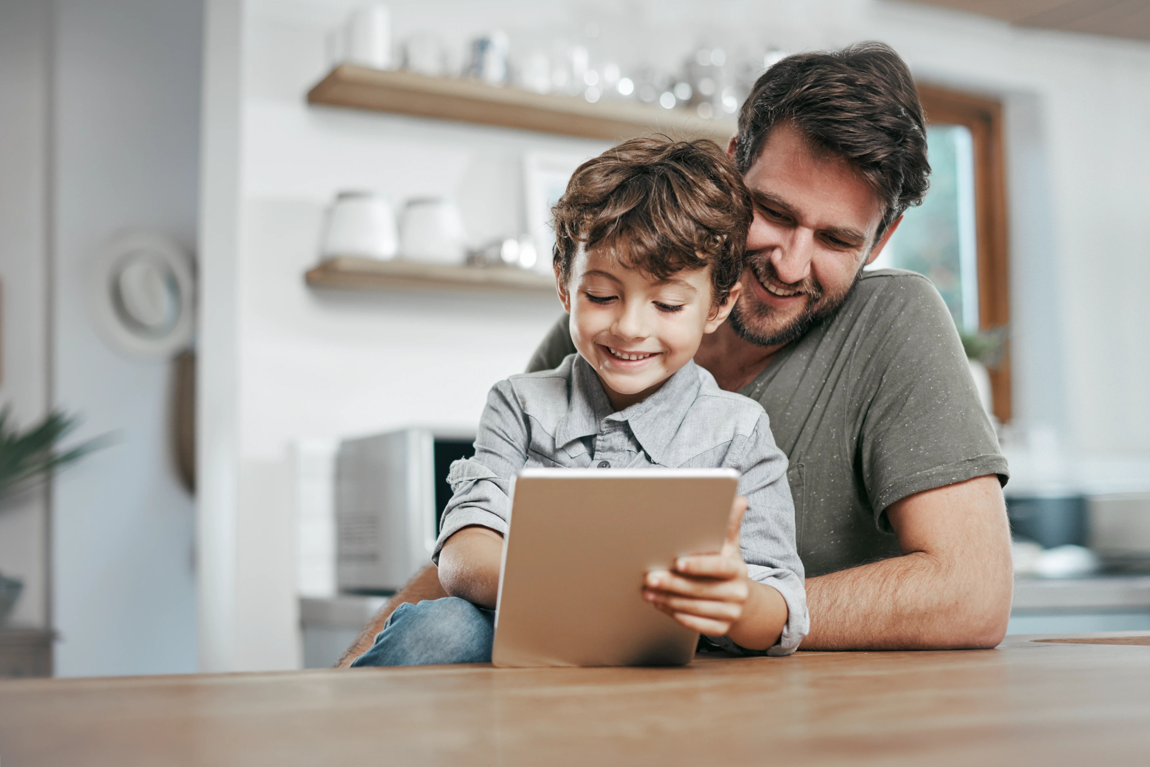 Vater mit Kleinkind genießen einen Videochat am Tabletcomputer