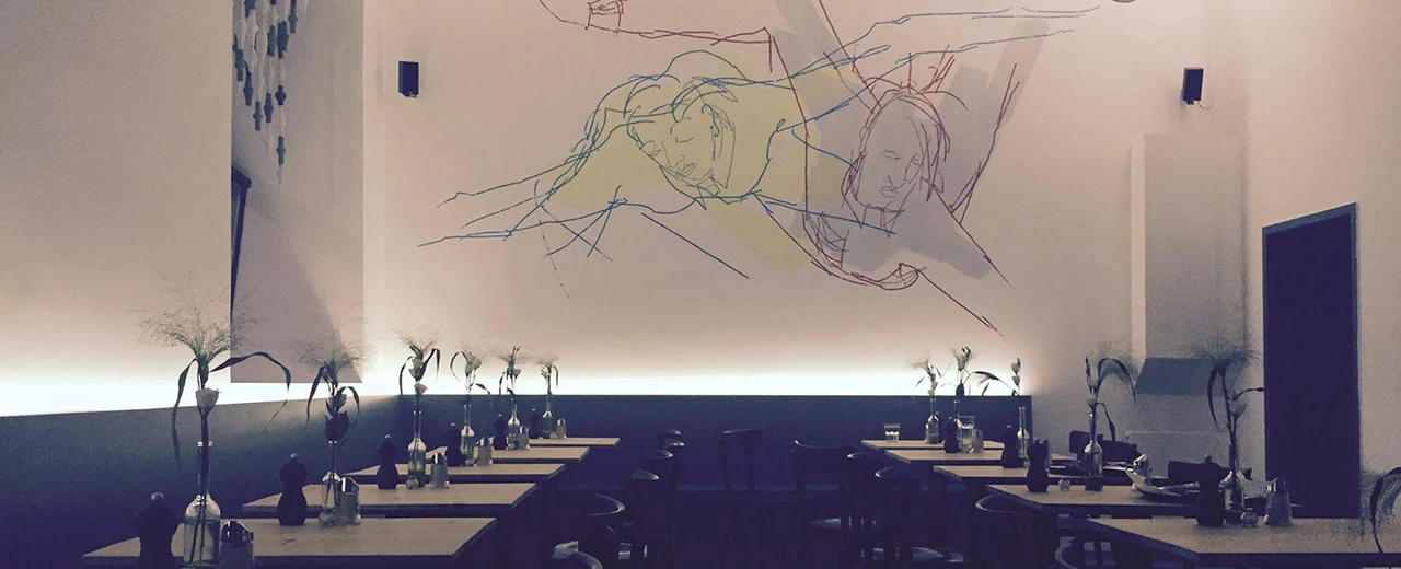 © Figar 1040 Minimalistisches Restaurant-Interieur mit abstrakter Wandkunst und mehreren gedeckten Tischen.