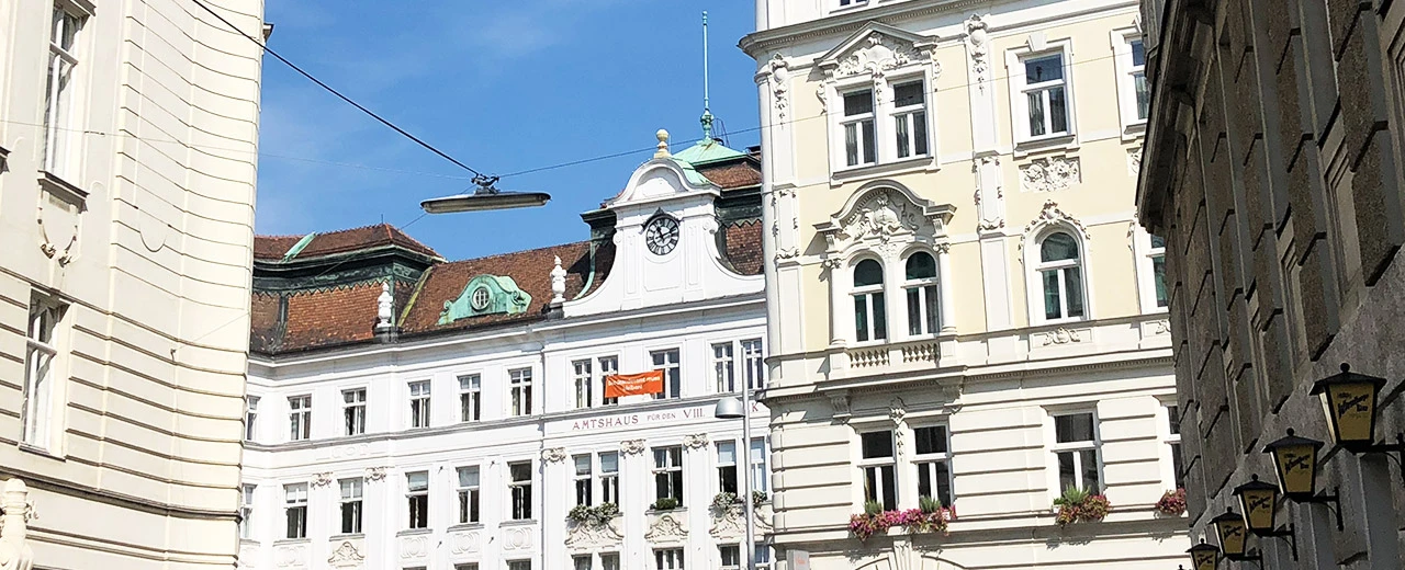 Historisches Stadtbild Wien: Barock- & Biedermeier-Gebäude, weiße Fassaden, Fenster, Blumenkästen.