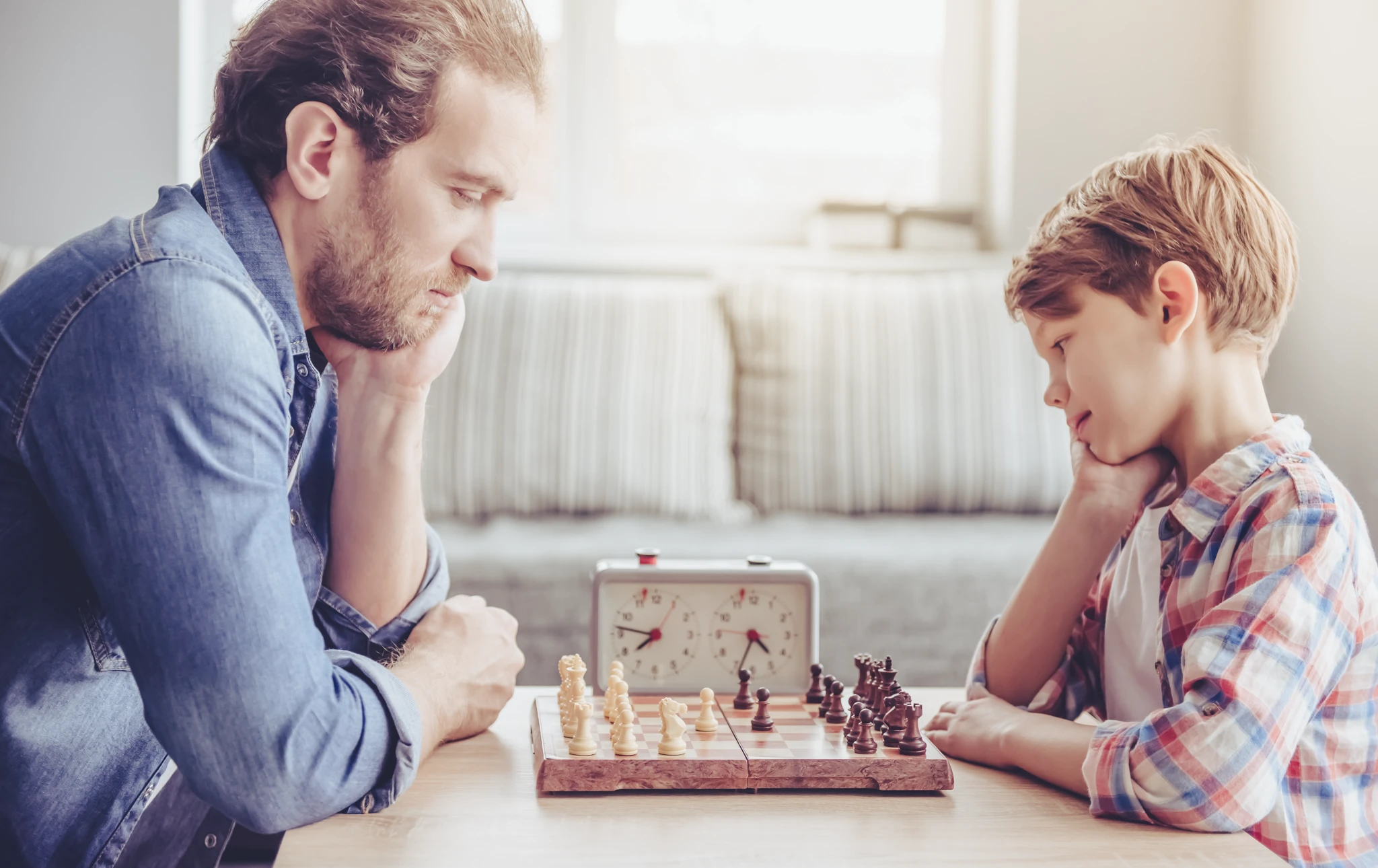 Vater und junger Sohn spielen Schach im Wohnzimmer