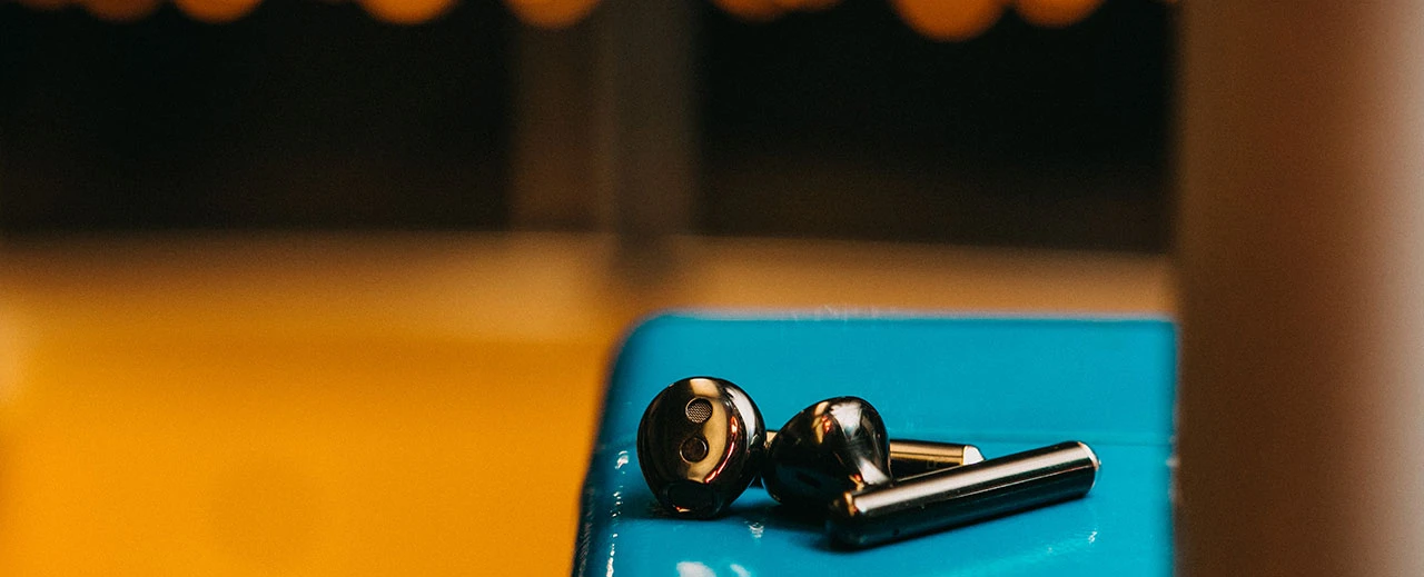 Hochwertiges Foto von schwarzen kabellosen Ohrhörern auf blauem Untergrund.