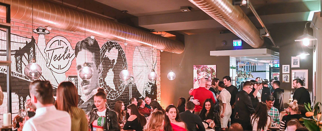 © Tesla Coffee & Concept Lebhafte Restaurant-Szene mit einem Wandgemälde von Nikola Tesla. Modernes Design mit industriellem Chic.