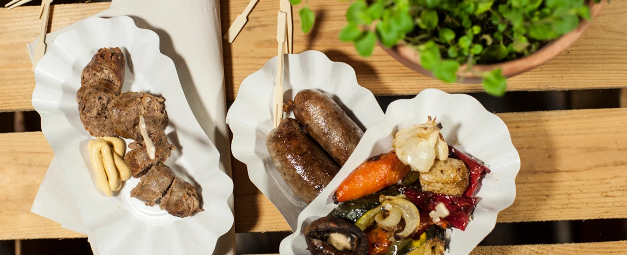 Gegrillte Würstchen und Gemüse auf Papptellern.  Foto mit Adobe Photoshop erstellt.