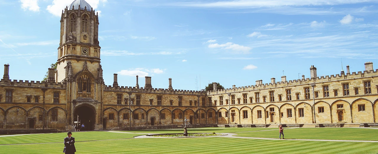 Historischer Innenhof mit gotischer Architektur, grünem Rasen und einem hohen Turm. Erstellt mit Adobe Photoshop.