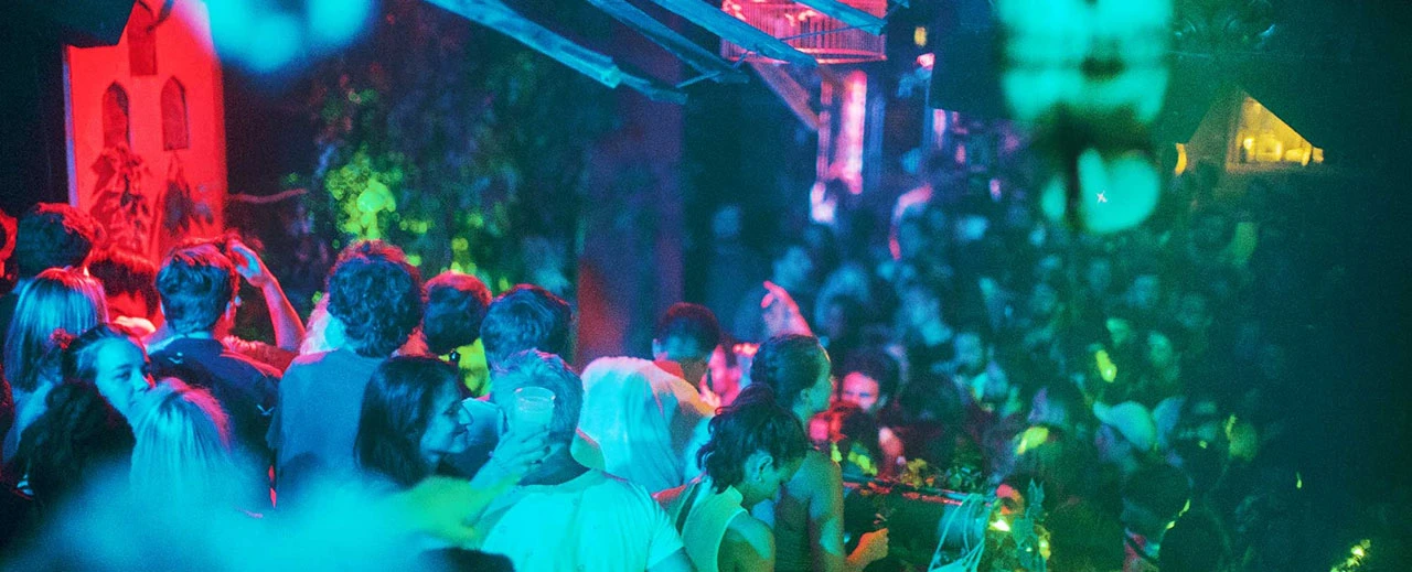 Tanzende Menschenmenge in einem Club mit blauen und roten Lichtern.  Lebhafte Partyatmosphäre.