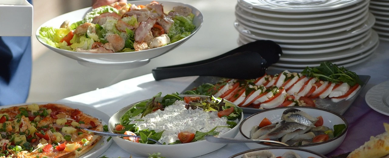 Buffet mit Caesar Salad, Caprese, verschiedenen Salaten, Hering & Pizza. Reichhaltige Auswahl an kalten Speisen.