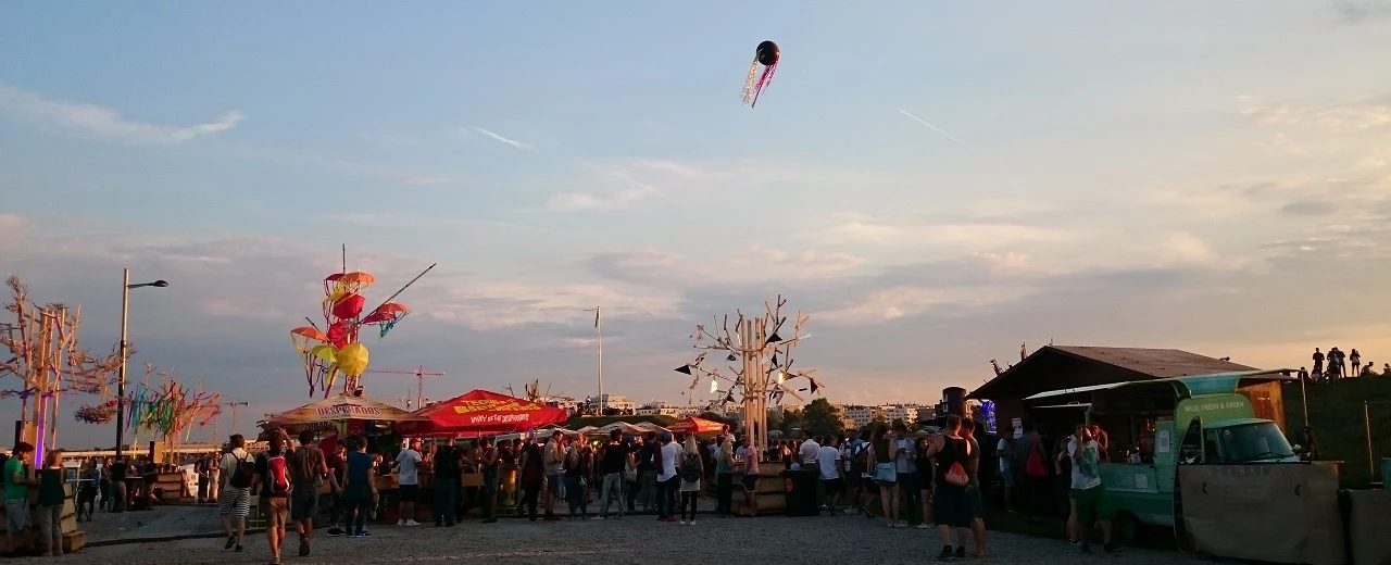 Festival am Abend: Essensstände, Menschen & Heißluftballon.