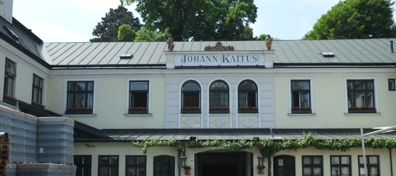 Restaurant Johann Kattus in Wien: zweistöckiges Gebäude, hellgelbe Fassade, dunkle Fenster, Metalldach.