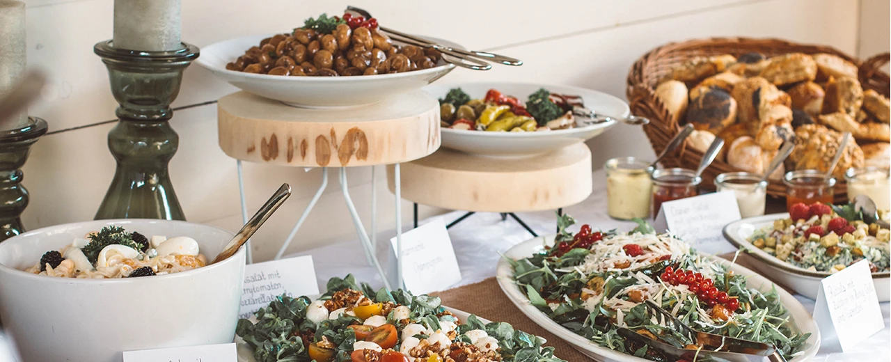 © Pia Kamp / Unsplash Buffet mit Salaten, Pilzen, Brot & Dips. Ideal für Events & Catering.