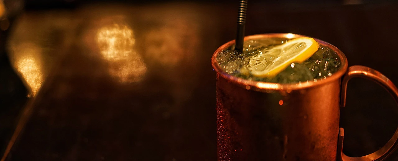 Erfrischender Cocktail in kupfernem Becher mit Eis und Zitronenscheibe. Mit Adobe Photoshop bearbeitet.