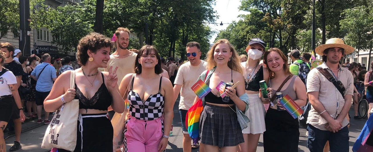 © Leni Kohlfürst Gruppe junger Menschen auf einer Pride Parade mit Regenbogenflaggen. Fröhliche und bunte Atmosphäre.