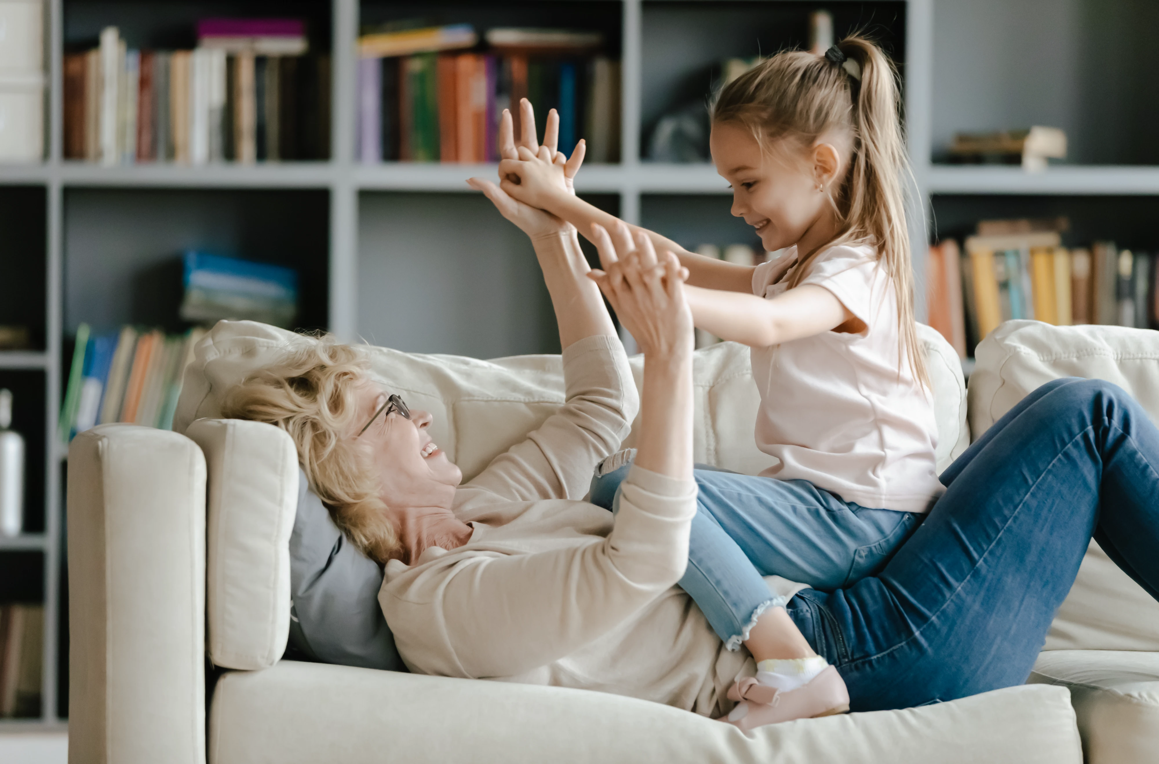 Ältere Dame spielt mit Mädchen auf dem Sofa