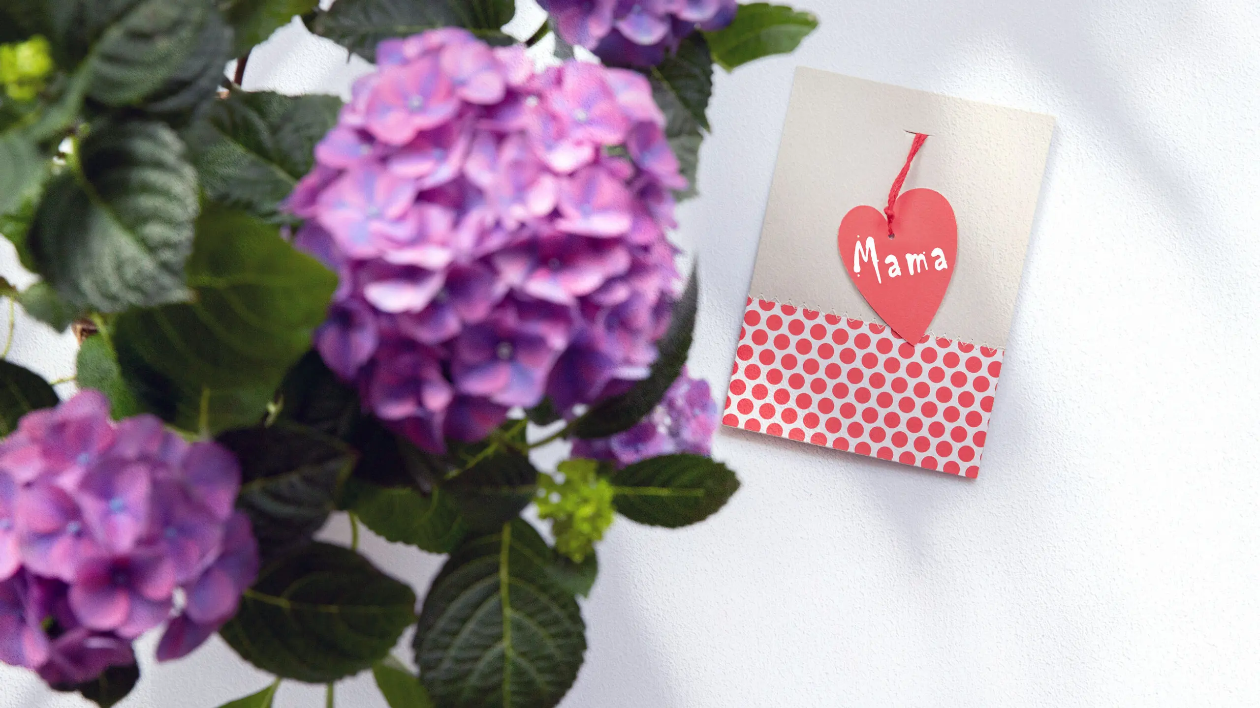 Muttertagskarte, die auf einem Tisch liegt. Im Vordergrund ist ein Blumenstrauß zu sehen.