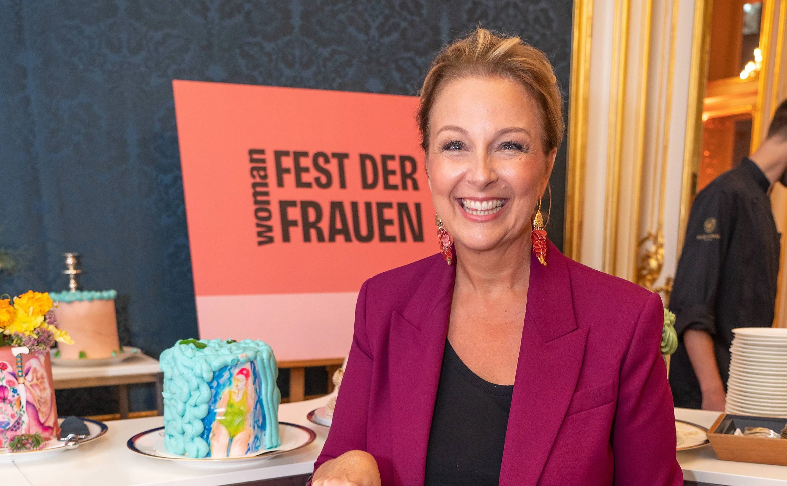 Euke Frank schneidet Kuchen an beim WOMAN Fest der Frauen.