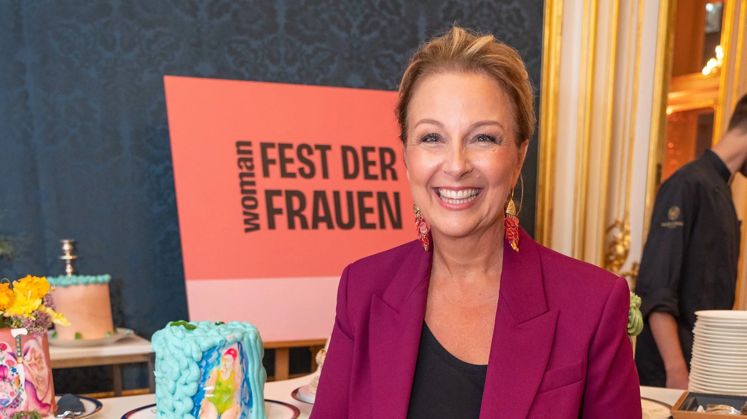 Euke Frank schneidet Kuchen an beim WOMAN Fest der Frauen.