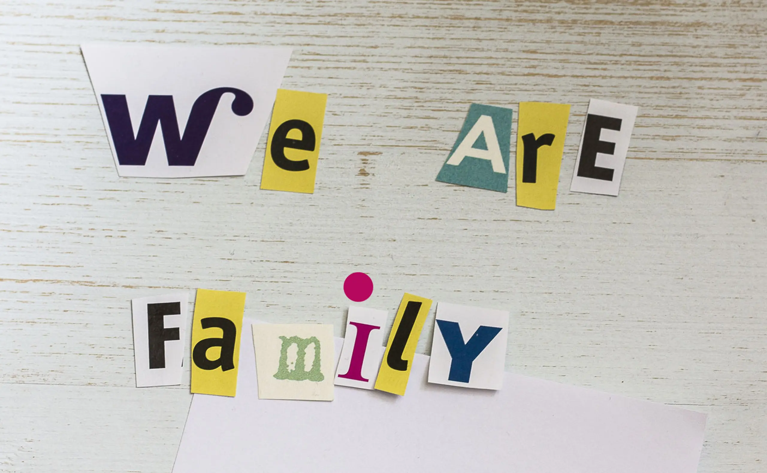 Schriftzug &quot;We are Family&quot; mit der Zeichnung eines Kindes, die Strichmännchen stellen eine Familie dar.