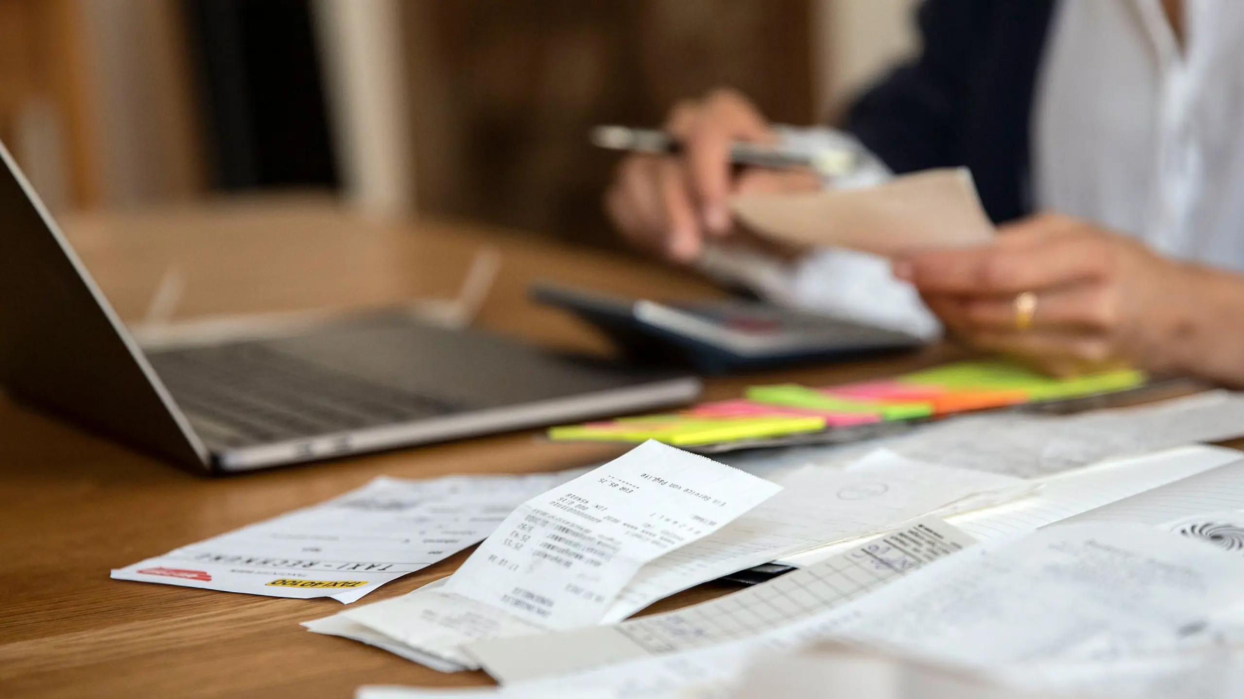 Tisch mit aufgeklappten Laptop und Rechnungen