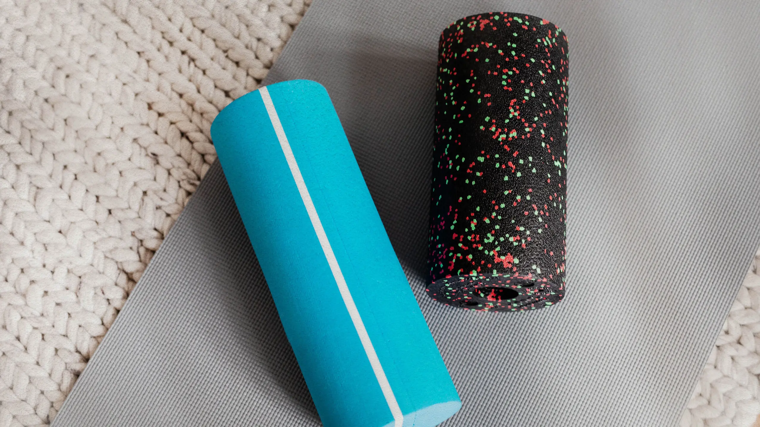 Zwei Faszienrollen, die auf einer Sportmatte liegen