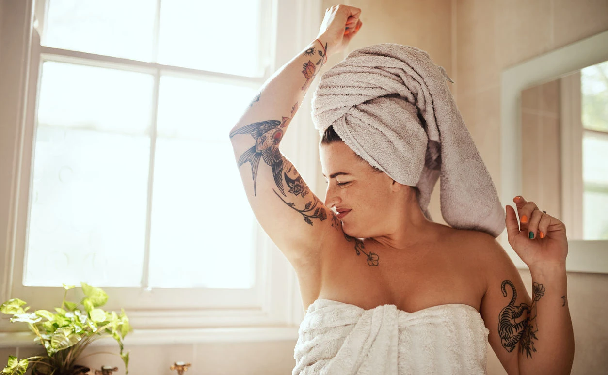 Frau im Badezimmer, die an ihrer Achsel riecht