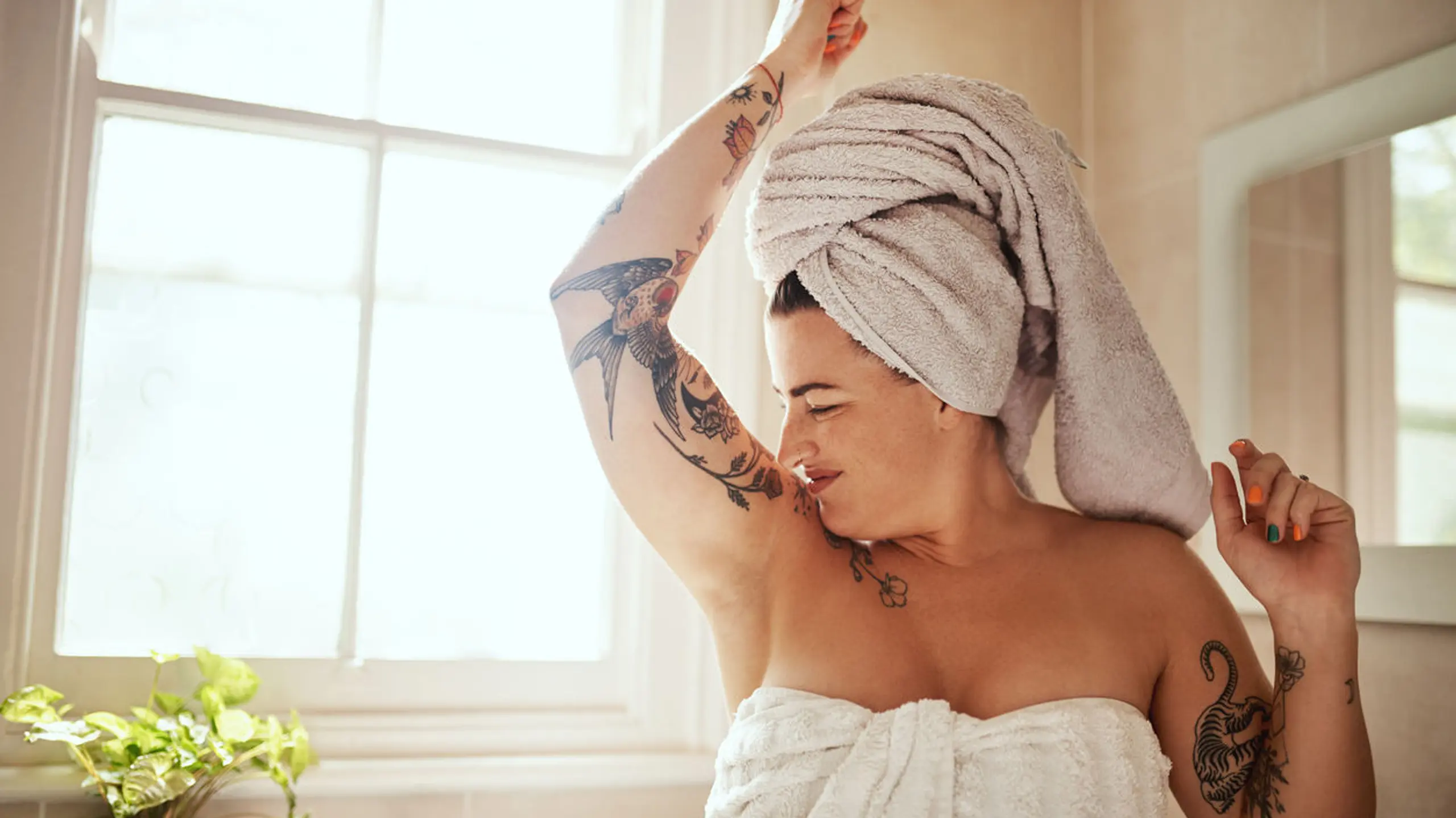 Frau im Badezimmer, die an ihrer Achsel riecht