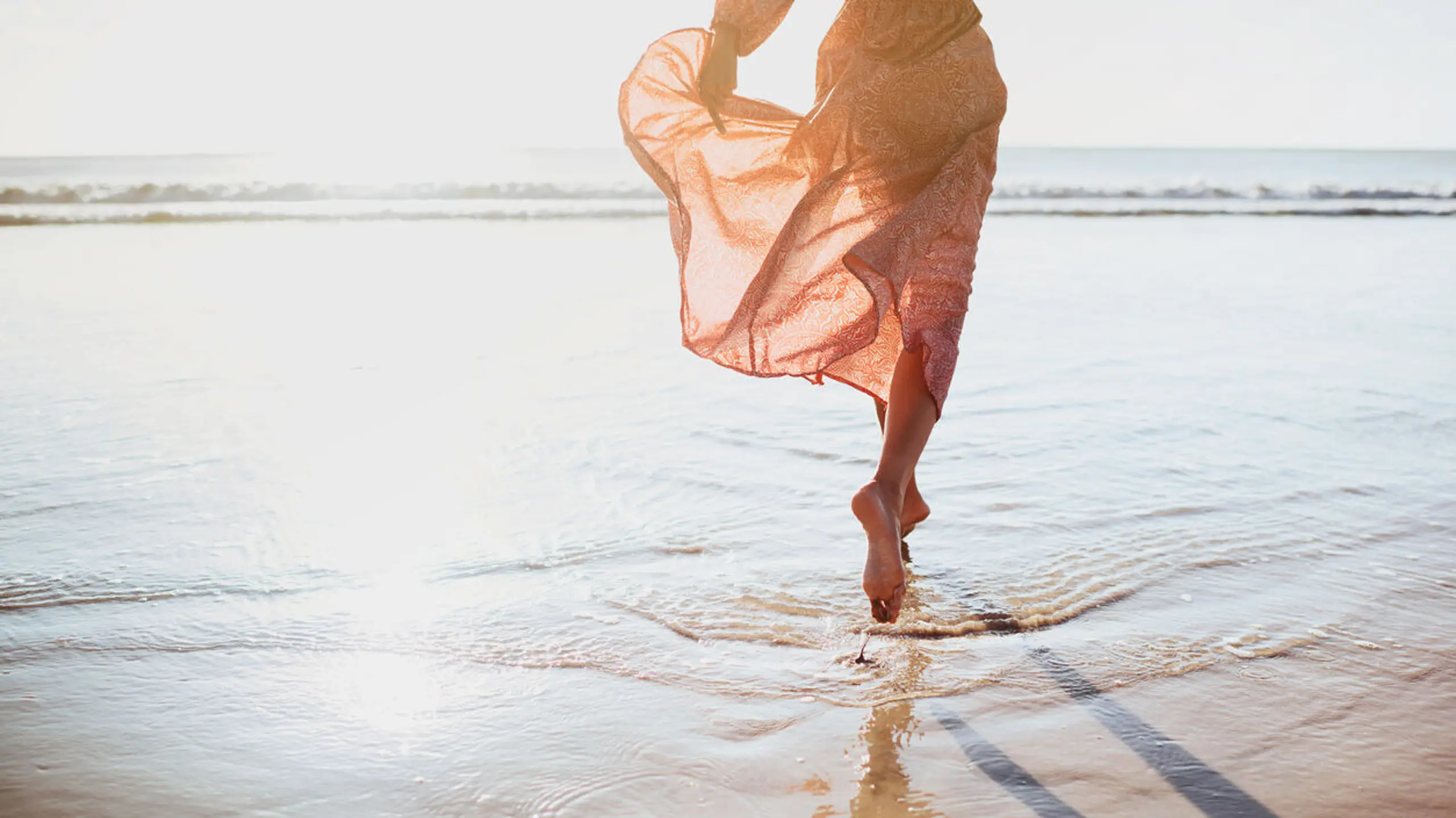 Frau im Strandkleid am Strand im Meer